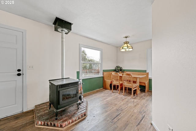 dining room with wood-type flooring, a textured ceiling, and a wood stove