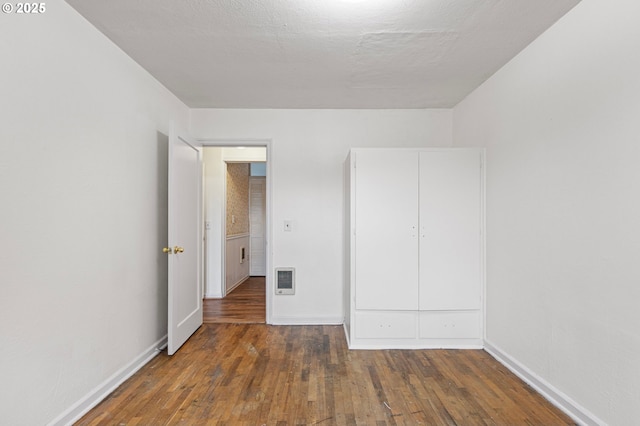 unfurnished bedroom with dark hardwood / wood-style flooring and a textured ceiling