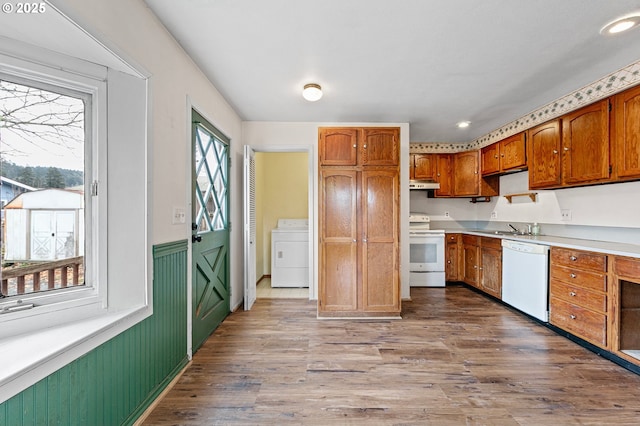 kitchen featuring white appliances, washer / clothes dryer, sink, and light wood-type flooring