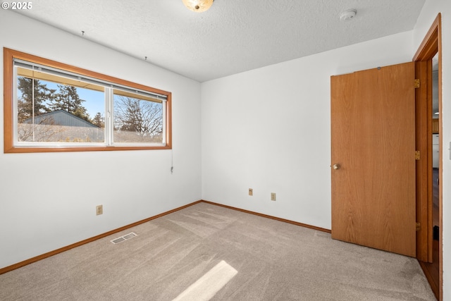 carpeted empty room featuring visible vents, baseboards, and a textured ceiling