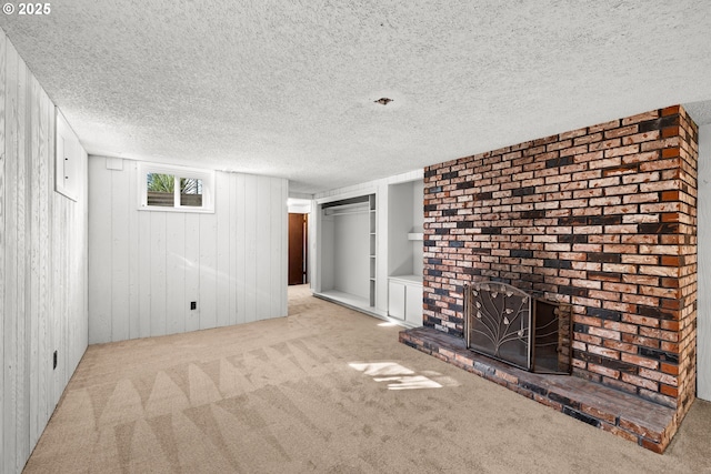 unfurnished living room featuring built in features, carpet, a fireplace, and a textured ceiling