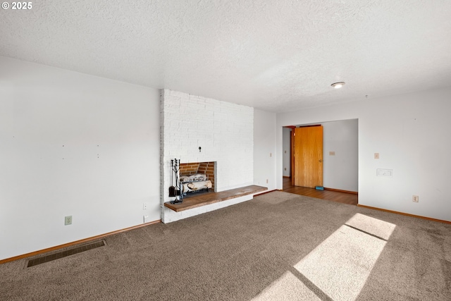 unfurnished living room featuring visible vents, baseboards, carpet, a fireplace, and a textured ceiling