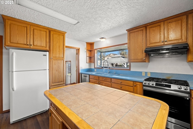 kitchen with brown cabinetry, dark wood-style flooring, a sink, stainless steel appliances, and under cabinet range hood