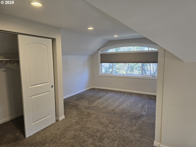 additional living space with dark colored carpet and lofted ceiling