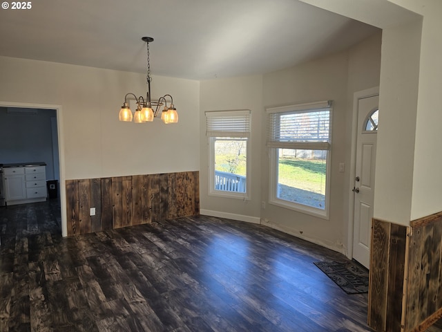 unfurnished dining area featuring an inviting chandelier and dark hardwood / wood-style flooring