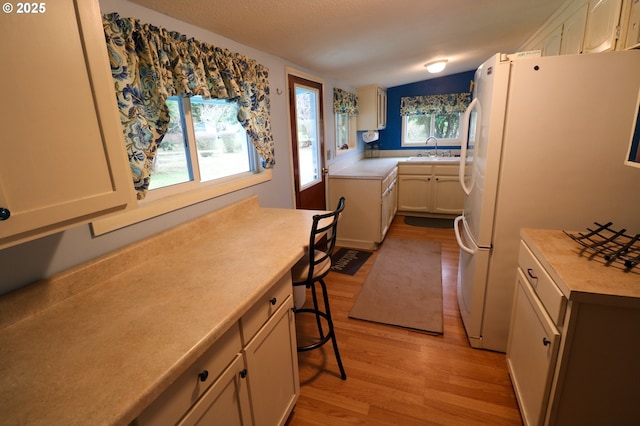 kitchen featuring sink, light wood-type flooring, white cabinets, and white fridge