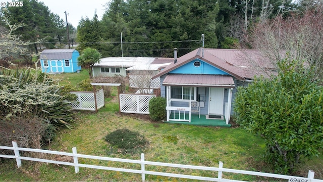 view of front of home featuring a shed, covered porch, and a front yard