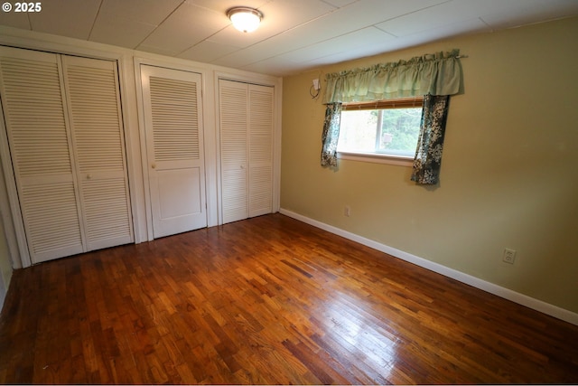 unfurnished bedroom with multiple closets and hardwood / wood-style floors