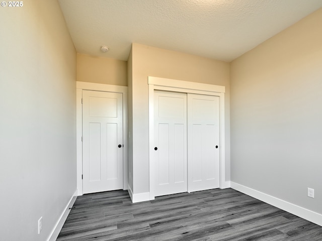 unfurnished bedroom with dark hardwood / wood-style floors, a textured ceiling, and a closet