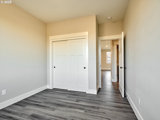 unfurnished bedroom featuring a closet and dark wood-type flooring