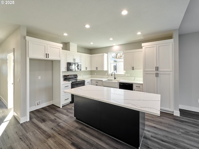 kitchen with a center island, dark wood-type flooring, black appliances, light stone counters, and white cabinetry