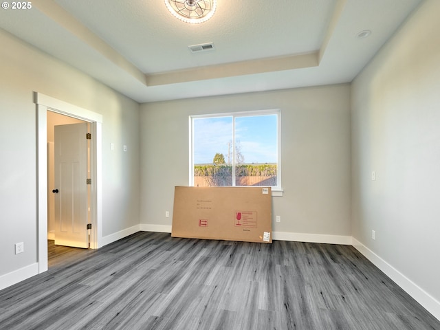 empty room with hardwood / wood-style floors and a raised ceiling