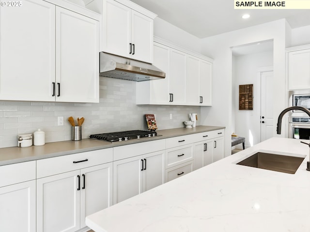 4958 N Adams Ct, Camas, WA 98607 - kitchen with under cabinet range hood, a sink, decorative backsplash, white cabinetry, and recessed lighting