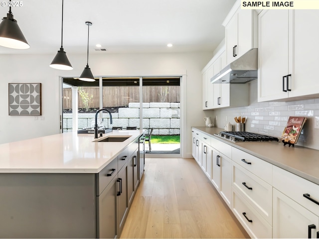 4958 N Adams Ct, Camas, WA 98607 - kitchen with under cabinet range hood, stainless steel gas cooktop, a sink, light wood finished floors, and gray cabinetry