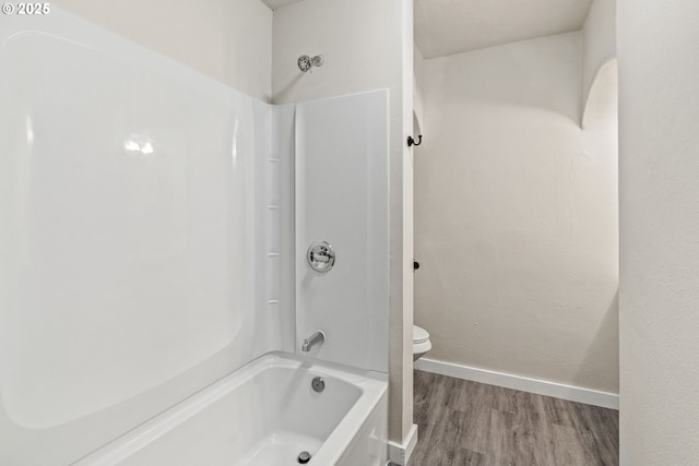 bathroom with wood-type flooring,  shower combination, and toilet