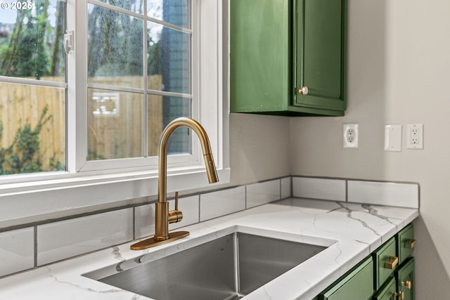 kitchen featuring light stone counters, sink, and green cabinetry