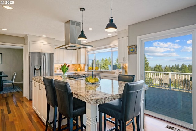 kitchen featuring light stone counters, island exhaust hood, backsplash, white cabinets, and a kitchen island