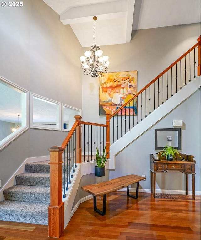 stairway with wood finished floors and a notable chandelier