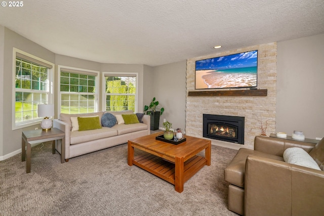 living area with a textured ceiling, a stone fireplace, carpet, and baseboards