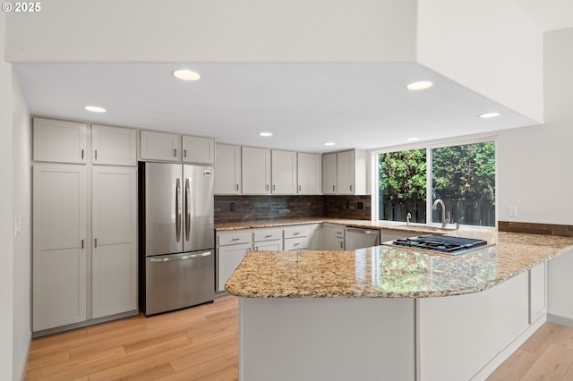 15080 SW 88th Ave, Portland, OR 97224 - kitchen with appliances with stainless steel finishes, a peninsula, light stone countertops, light wood finished floors, and recessed lighting