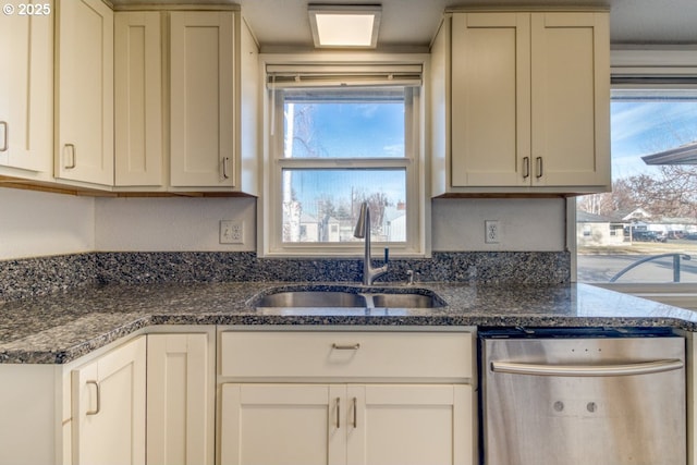 kitchen featuring dishwasher, sink, a wealth of natural light, and dark stone counters