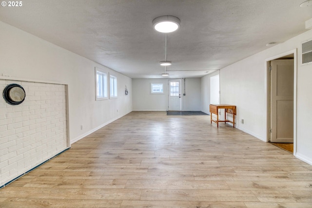 unfurnished room with light hardwood / wood-style flooring and a textured ceiling