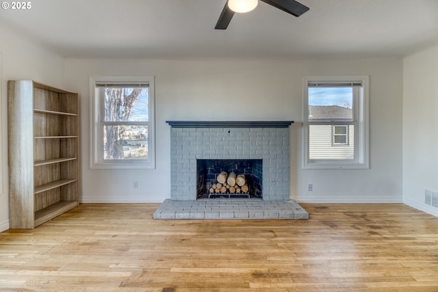 unfurnished living room with light hardwood / wood-style flooring, ceiling fan, a fireplace, and a healthy amount of sunlight