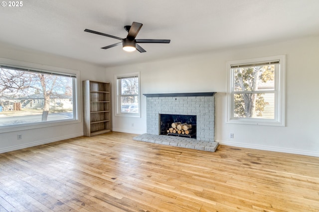 unfurnished living room with ceiling fan, a fireplace, and light hardwood / wood-style flooring