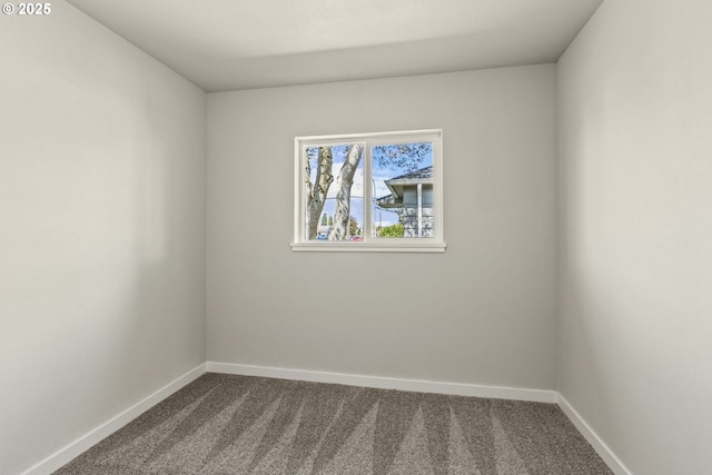 unfurnished room with baseboards and dark carpet