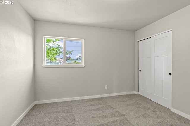 unfurnished bedroom featuring baseboards, a closet, and carpet floors