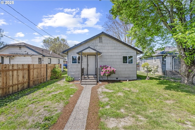 view of front facade with entry steps, a front lawn, and fence