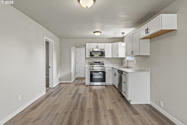 kitchen with light wood-style floors, white cabinets, appliances with stainless steel finishes, and a sink