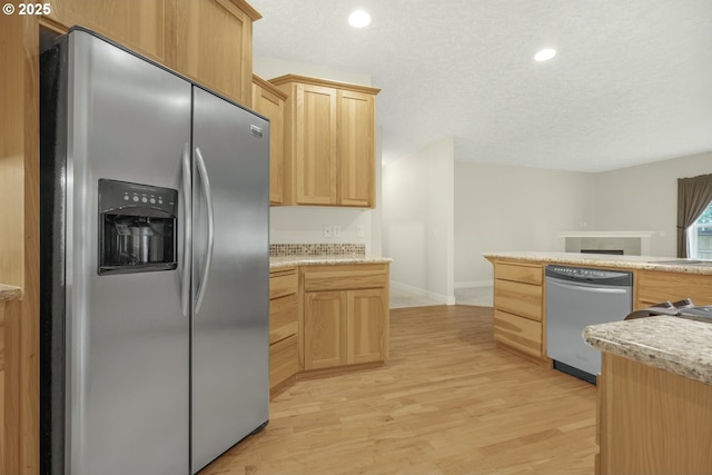 kitchen with light wood finished floors, light brown cabinetry, appliances with stainless steel finishes, and light countertops