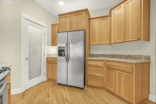 kitchen featuring light wood-style floors, light stone countertops, stainless steel fridge with ice dispenser, and light brown cabinetry