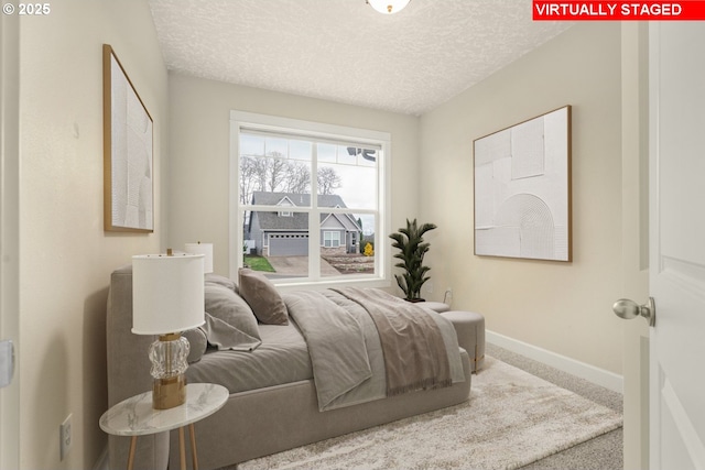 carpeted bedroom with a textured ceiling and baseboards