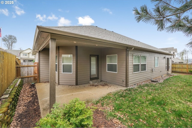 back of house featuring a patio area, a fenced backyard, a shingled roof, and a lawn