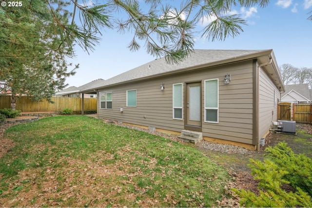 back of property with entry steps, a fenced backyard, and a yard