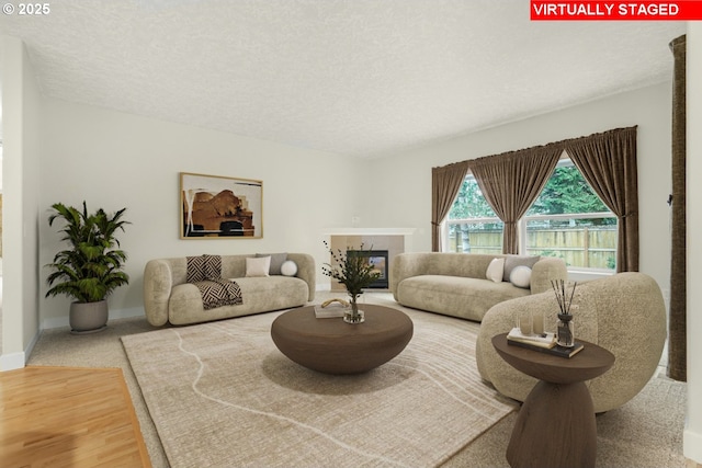 living area featuring a textured ceiling, a glass covered fireplace, and baseboards