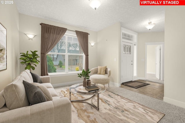 living area featuring carpet floors, baseboards, a textured ceiling, and tile patterned floors