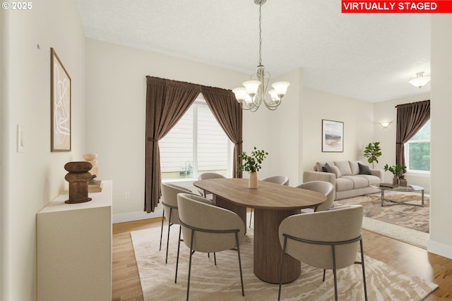 dining space featuring a chandelier, light wood-type flooring, and baseboards