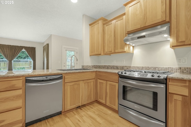 kitchen featuring light brown cabinets, a sink, appliances with stainless steel finishes, range hood, and light wood finished floors