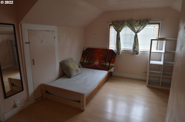 bedroom featuring baseboards, vaulted ceiling, and wood finished floors