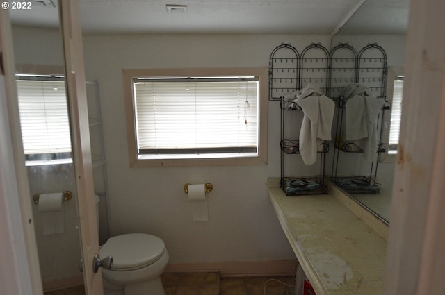 bathroom with a wealth of natural light, visible vents, toilet, and baseboards