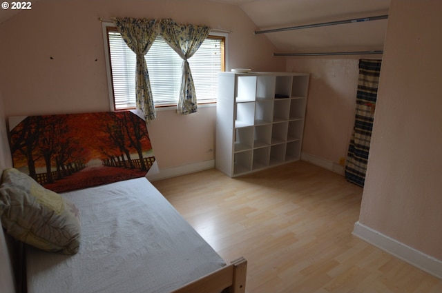bedroom with baseboards, vaulted ceiling, and wood finished floors