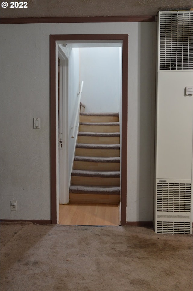 staircase featuring carpet flooring, a heating unit, and baseboards