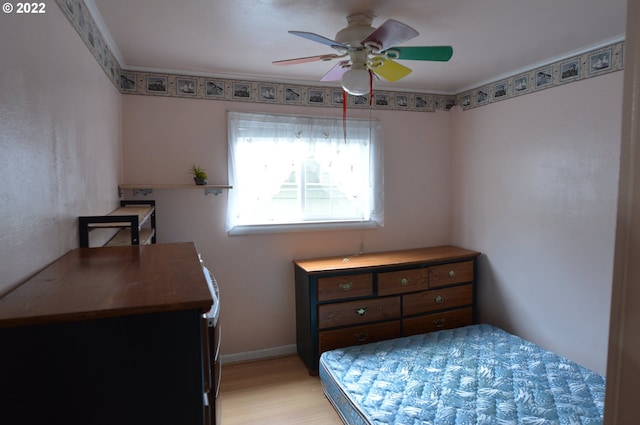 bedroom featuring ceiling fan, crown molding, light wood-type flooring, and baseboards