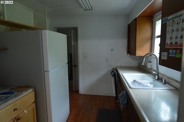 kitchen featuring freestanding refrigerator, light countertops, a sink, and dark wood finished floors