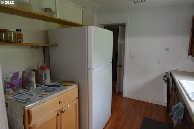 kitchen with light countertops, wood finished floors, open shelves, and freestanding refrigerator