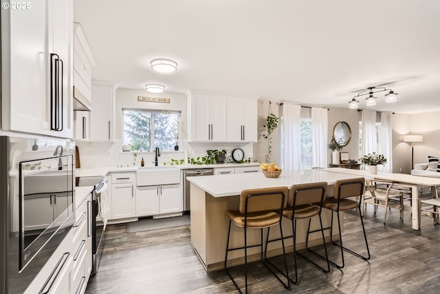 kitchen featuring a kitchen bar, a center island, white cabinetry, and sink