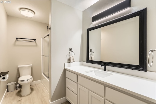 full bathroom featuring shower / bath combination with glass door, hardwood / wood-style floors, vanity, and toilet